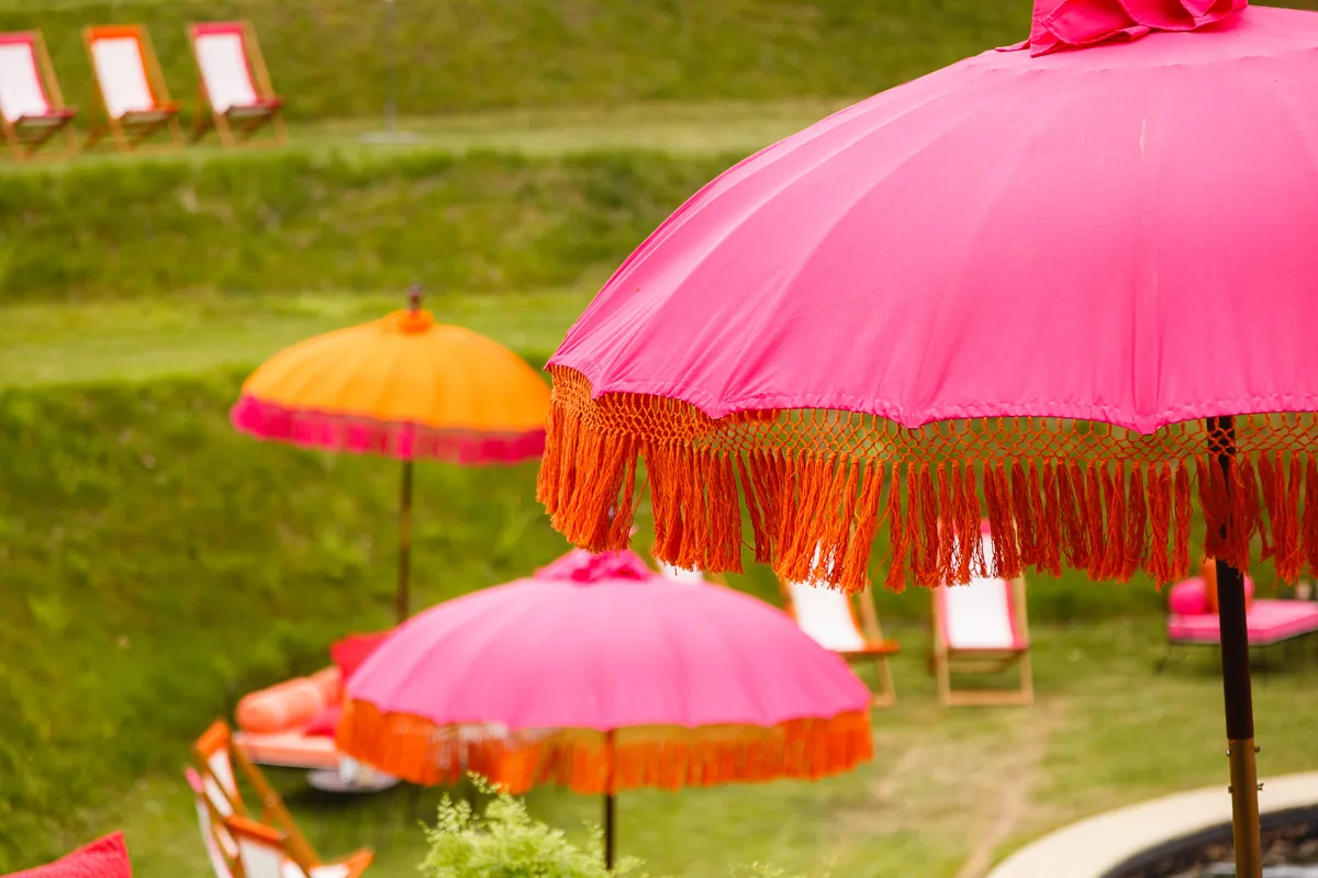 Pink and orange parasols on grassy lawn.