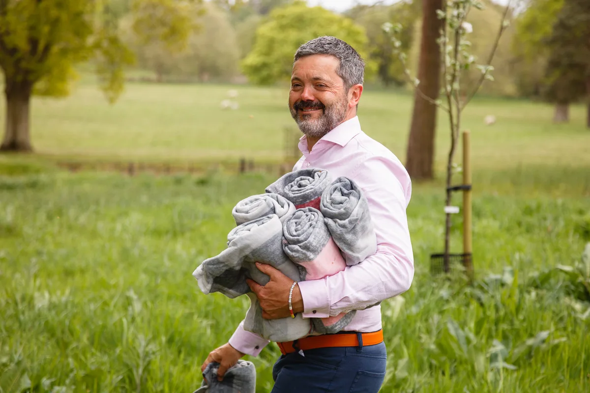 Man in pink carrying grey blankets in field