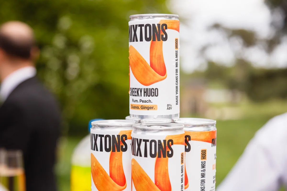 Stack of Cheeky Hugo canned drinks outdoors.