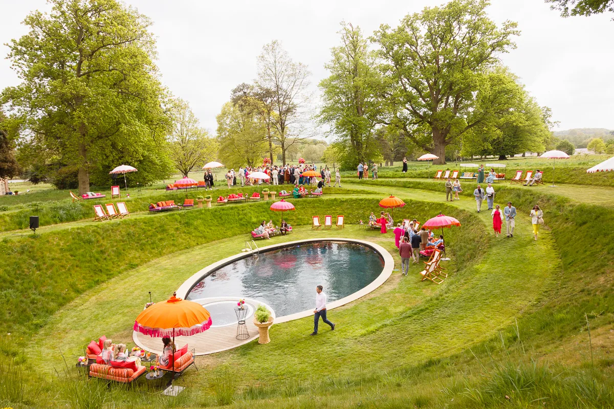 Outdoor garden party with pond and colourful umbrellas.