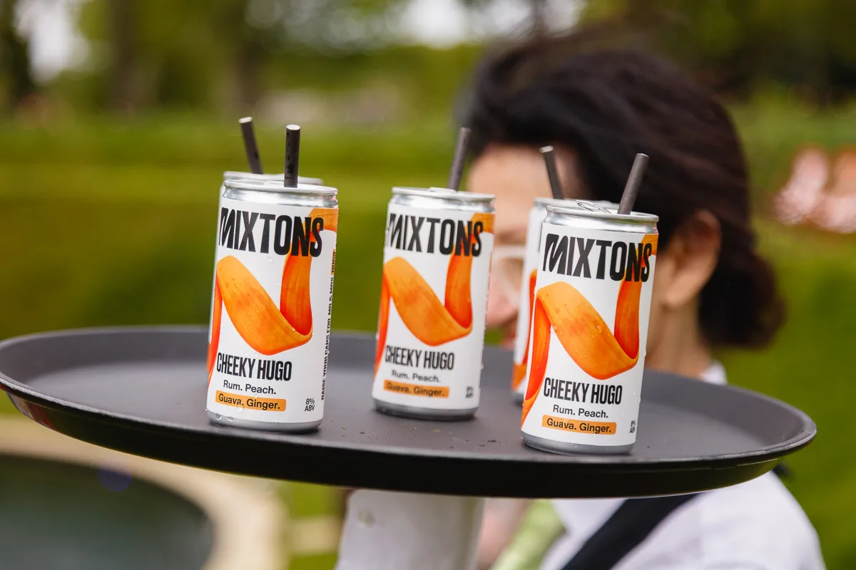 Tray with Mixtons Cheeky Hugo cans outdoors.