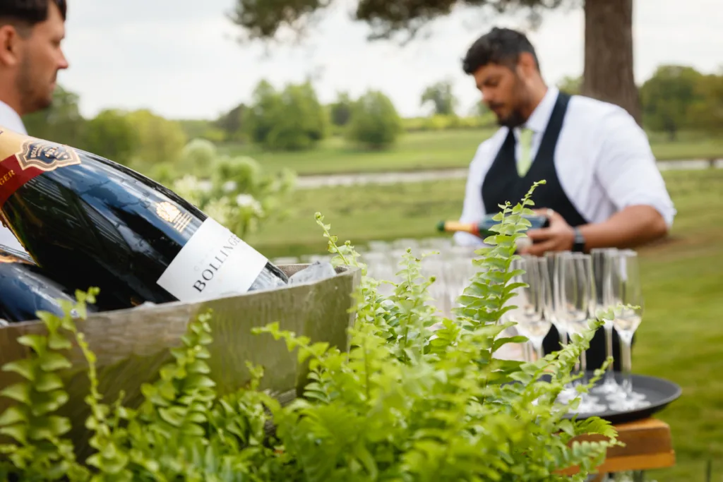 Outdoor champagne service with wine bottles and glasses.