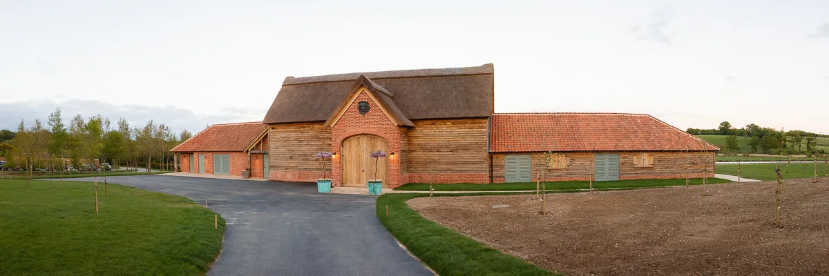Rustic barn with thatched roof in countryside setting.
