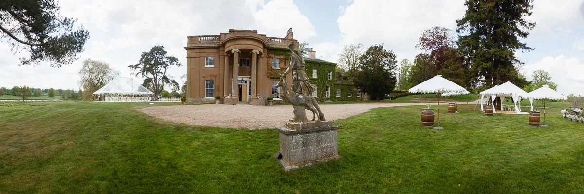 Historic mansion with gardens and white marquee tents.