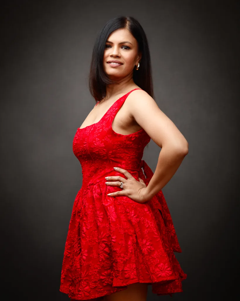 Woman in red floral dress, smiling confidently.