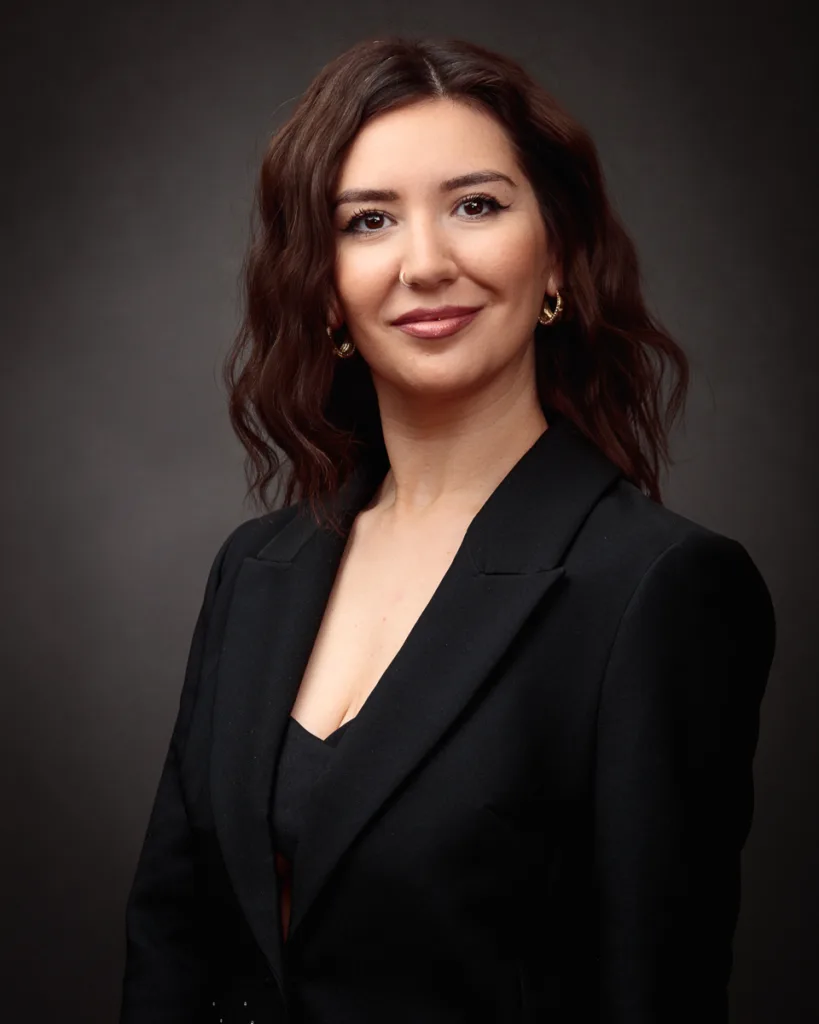 Professional woman in black blazer smiling confidently.