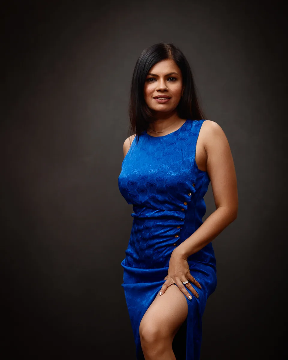 Person in elegant blue dress posing confidently.