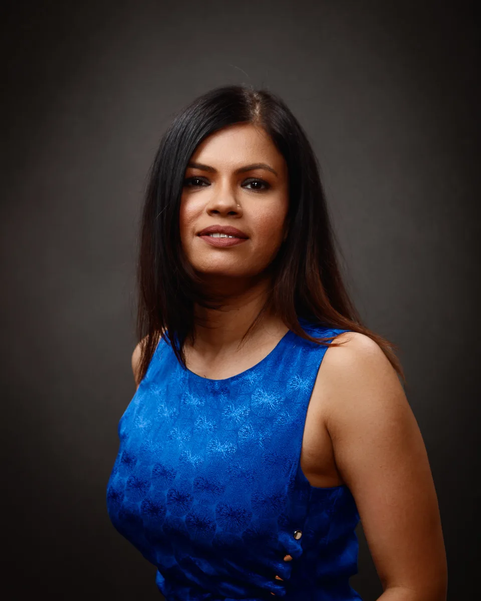 Woman in blue dress smiling at camera.