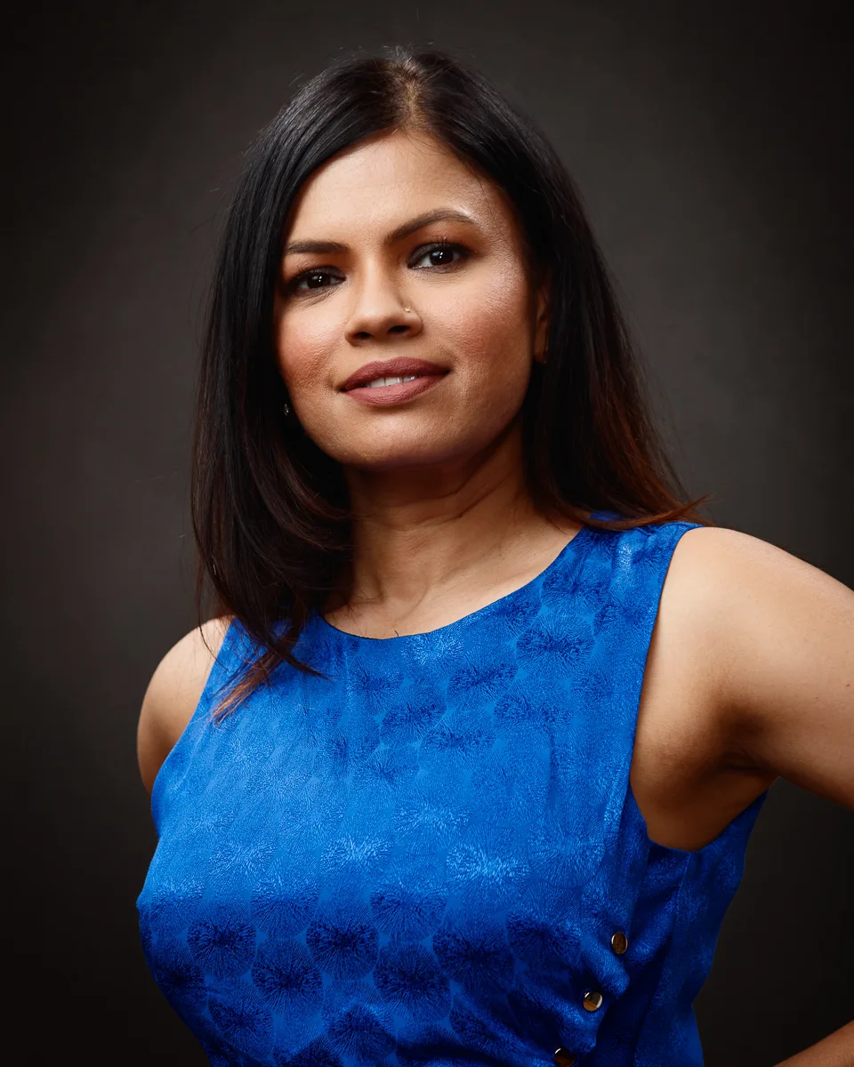 Woman in blue dress posing confidently.