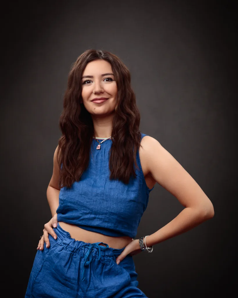 Smiling woman in blue outfit, hands on hips.