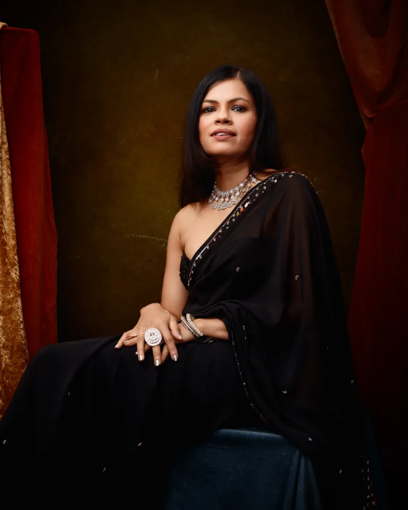 Woman in elegant black saree with jewellery.