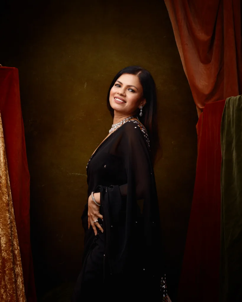 Woman in elegant black dress, smiling confidently.
