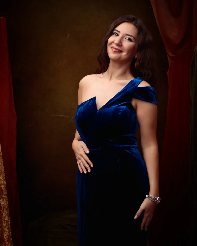 Woman in elegant blue dress smiling warmly.