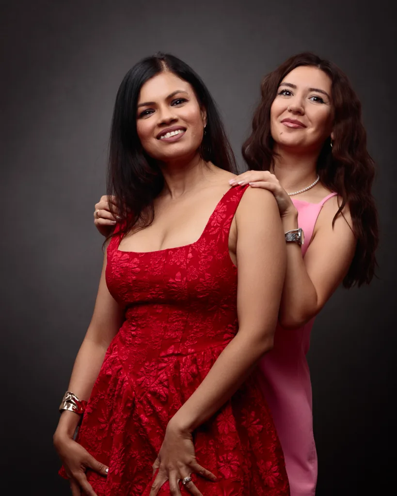 Two women posing in elegant dresses.