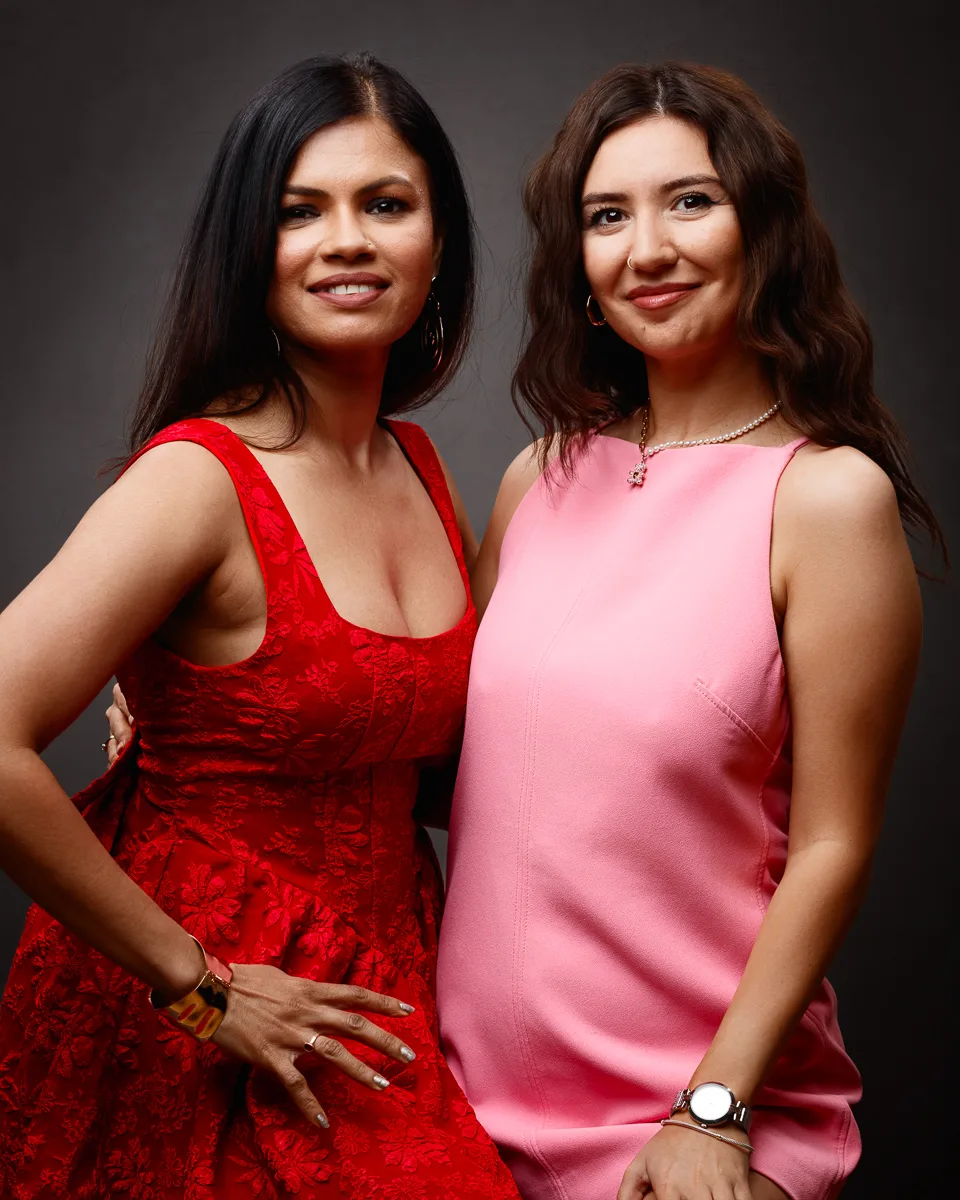 Two women posing in colourful dresses.