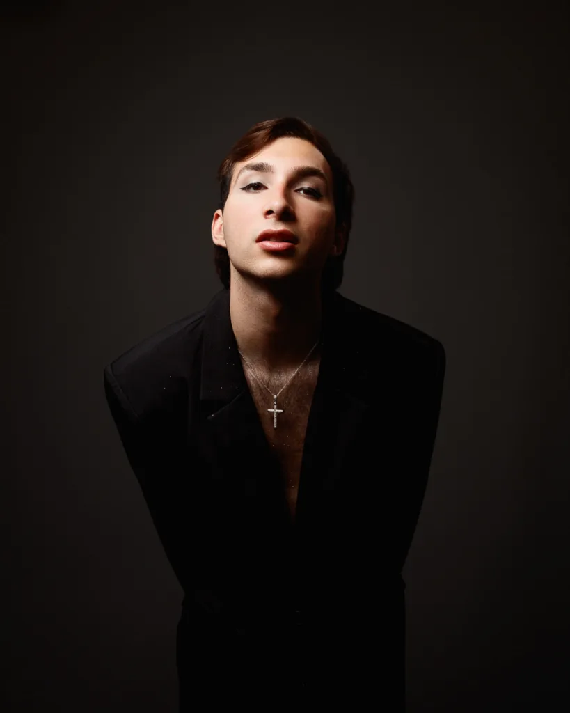 Person in dark clothing with silver cross necklace.