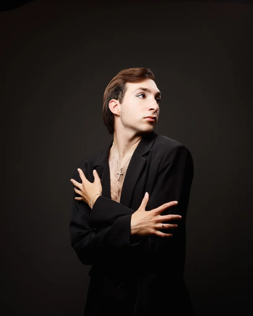 Person posing in black jacket, looking sideways.