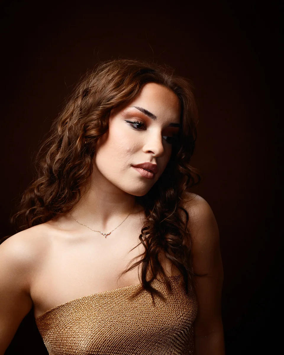 Woman in strapless gold dress, curly hair.