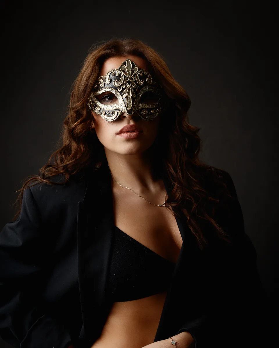 Woman in ornate mask and black attire.