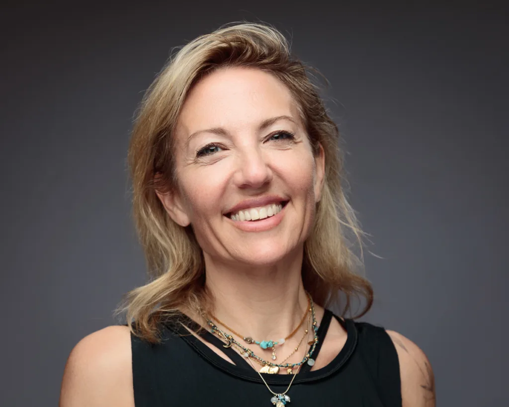 Smiling woman with blonde hair and necklaces.