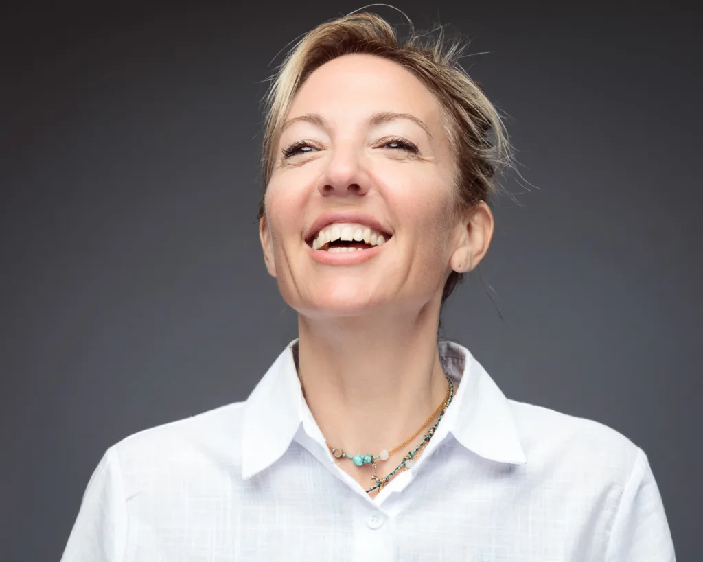 Smiling person wearing a white shirt, grey background.