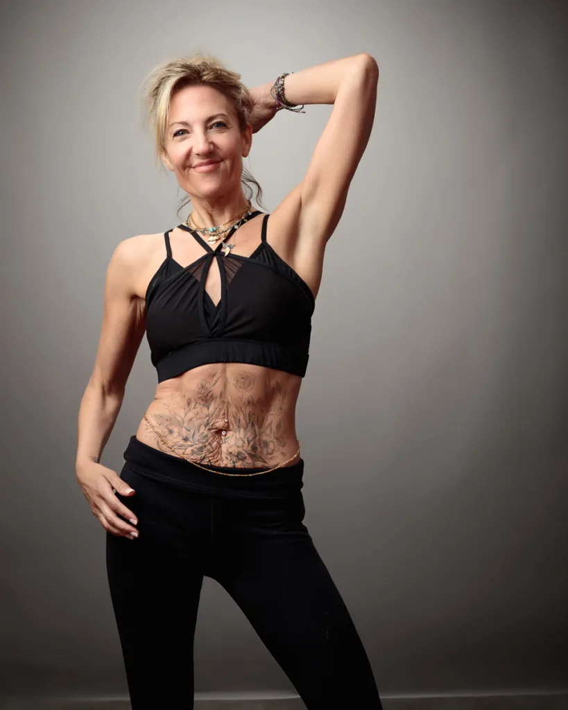 Woman in fitness clothing with tattoos posing confidently.