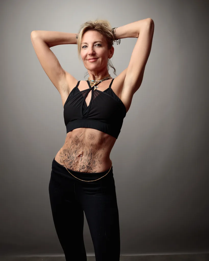 Woman posing with floral tattoo on stomach.