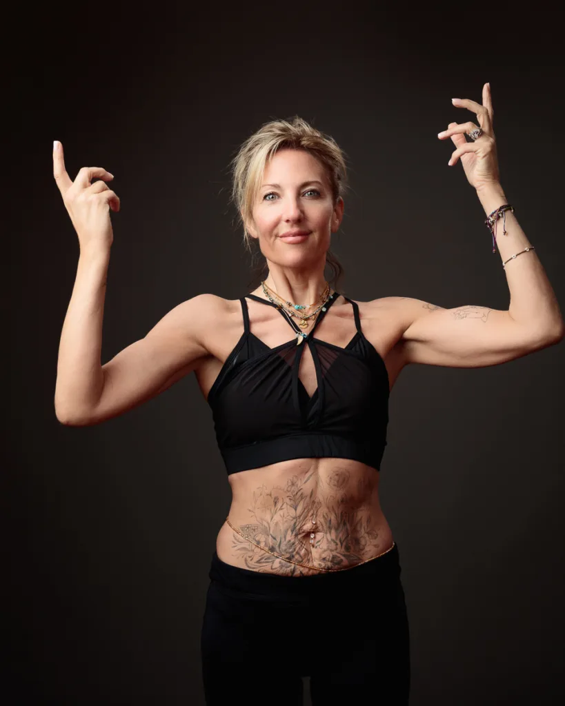 Woman posing in black sportswear with tattoos.