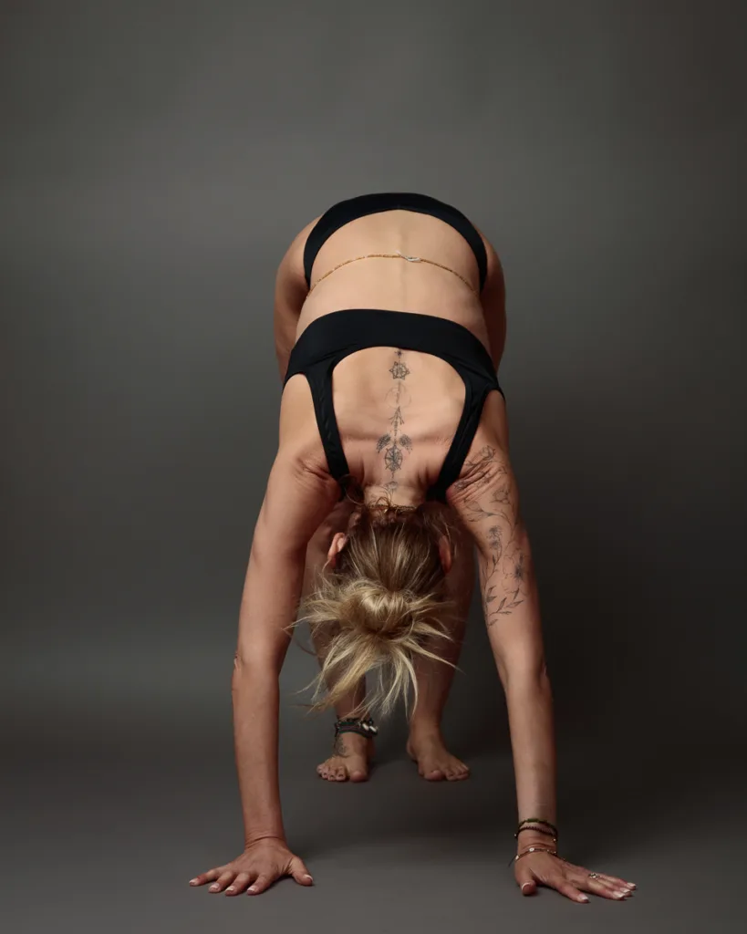 Woman performing yoga pose with tattoos.