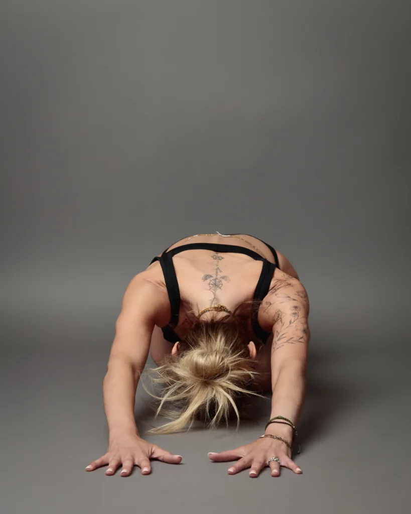 Person practicing child's pose yoga position on grey background.