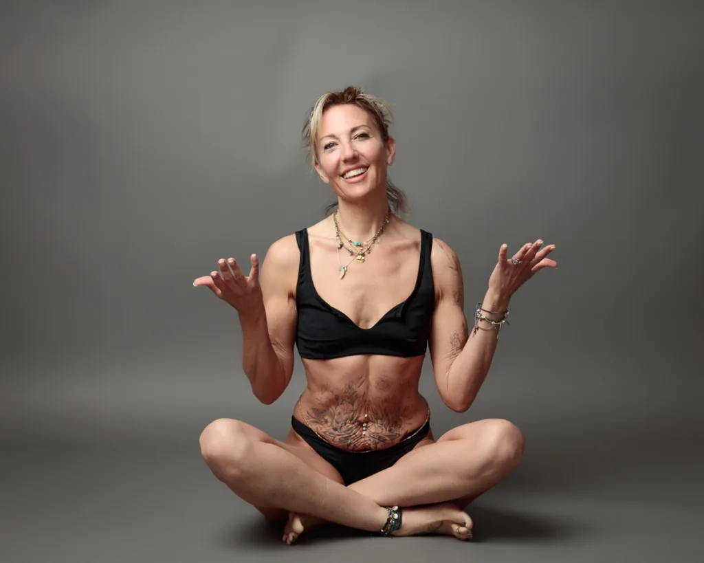 Woman in black underwear smiling seated cross-legged