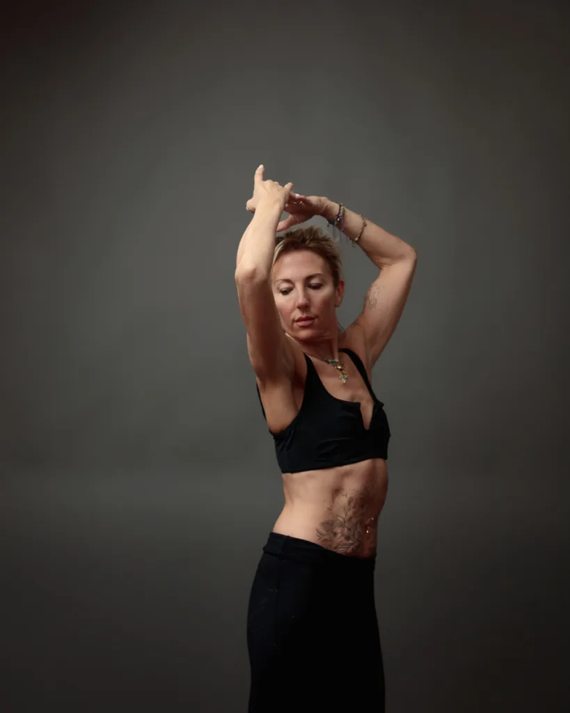 Woman posing in black sports attire against grey background.