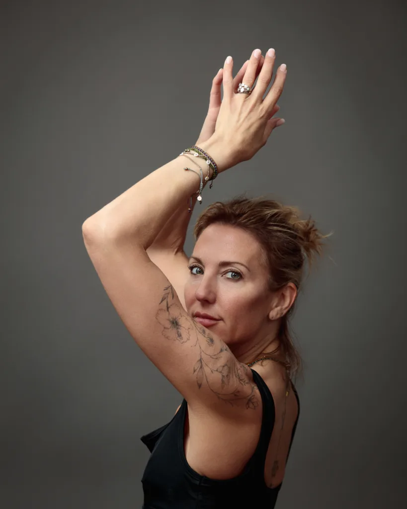 Woman with floral arm tattoo raises arms gracefully