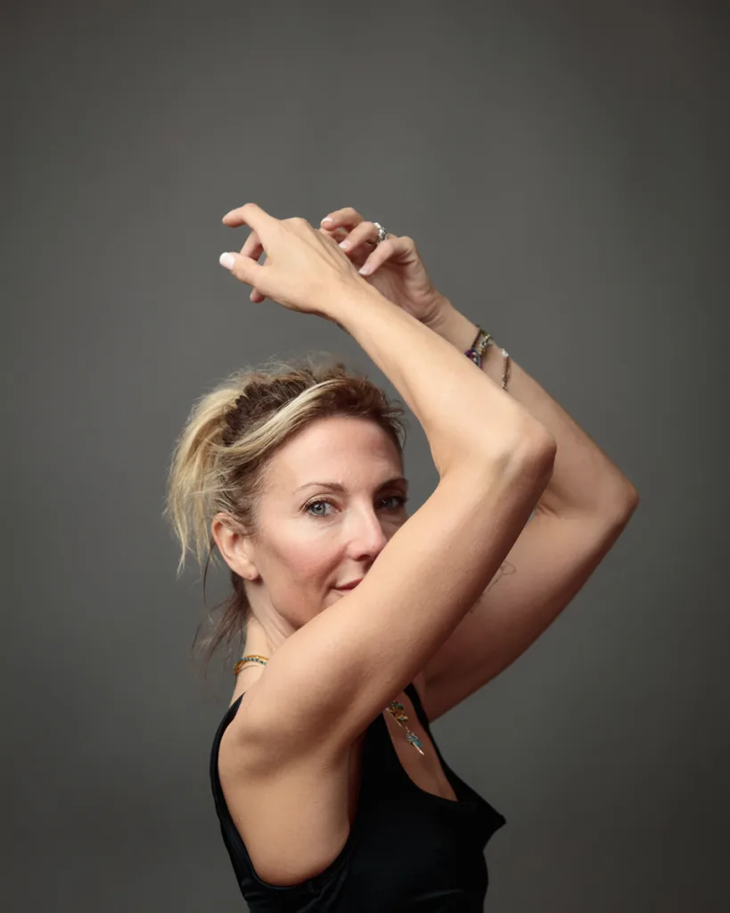 Woman posing with raised arms in studio portrait.