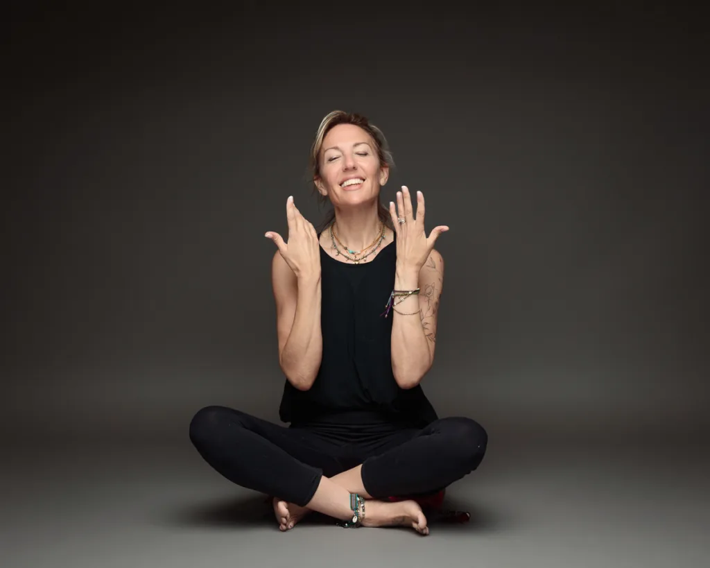 Smiling woman in yoga pose against dark background.