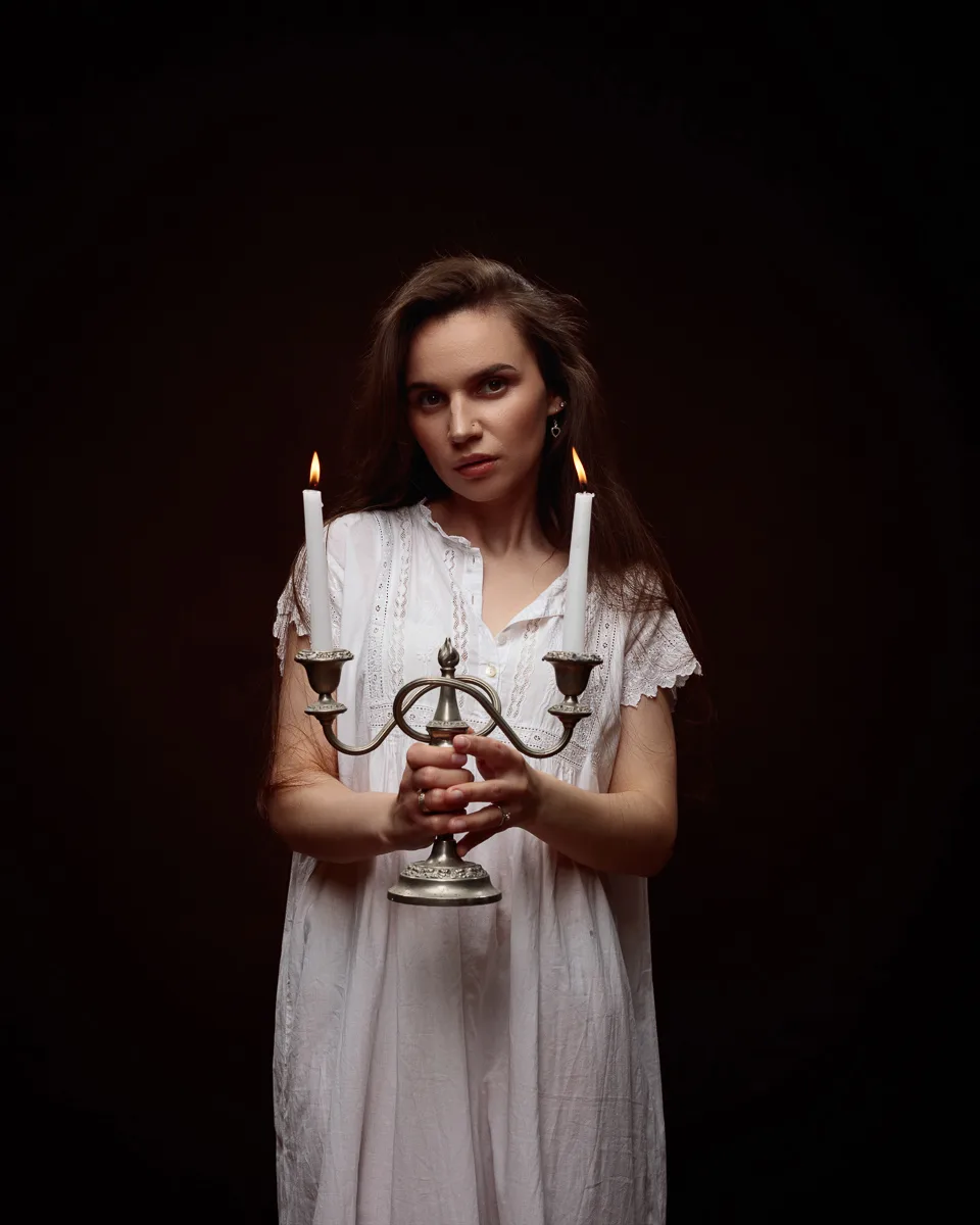 Person holding vintage candle holder in dark setting.