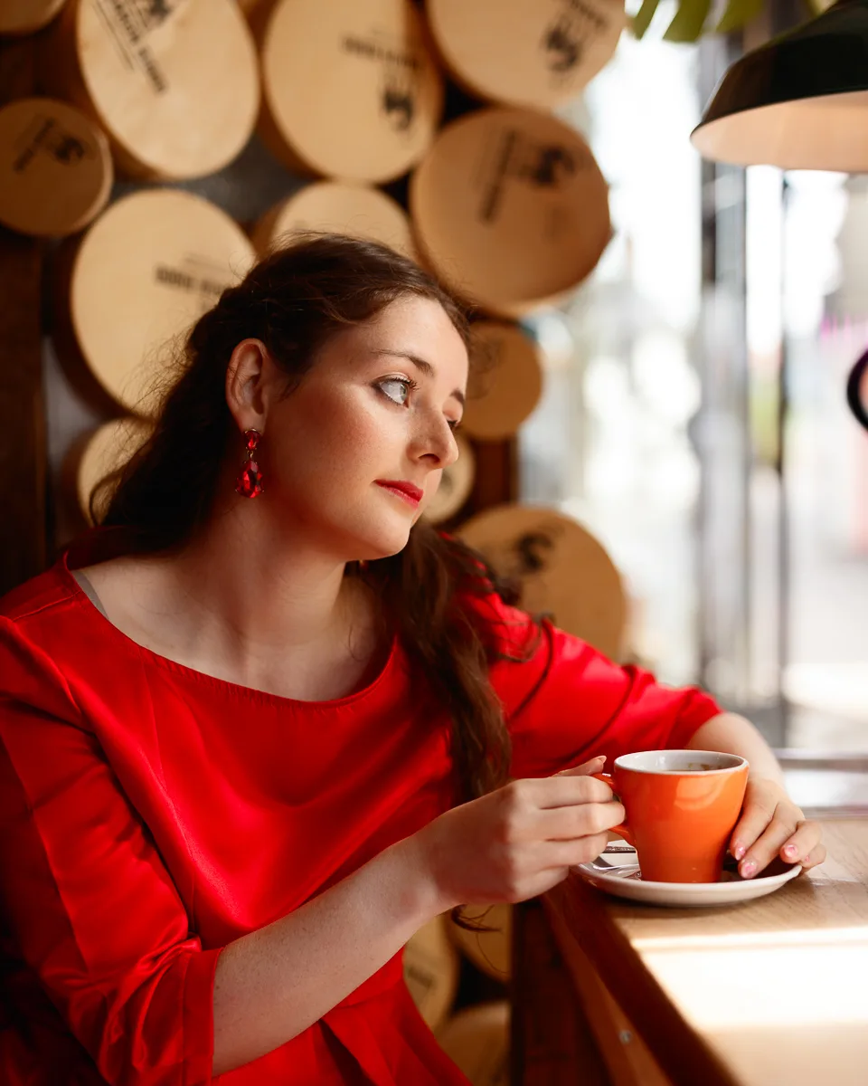 Woman in a red dress drinking coffee in a café in Halesworth