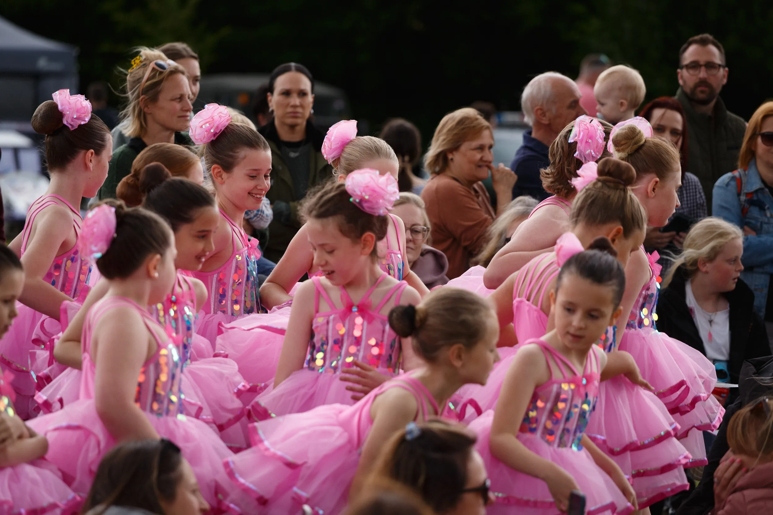 Young dancers in pink dresses performing outdoors.