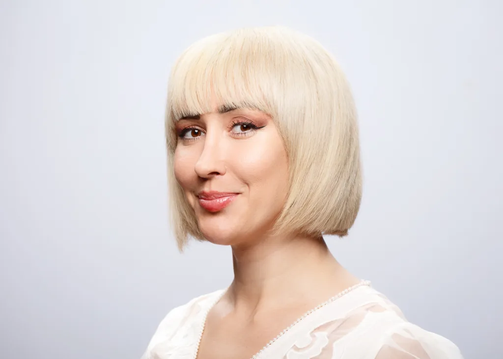 Smiling person with short blonde hair.