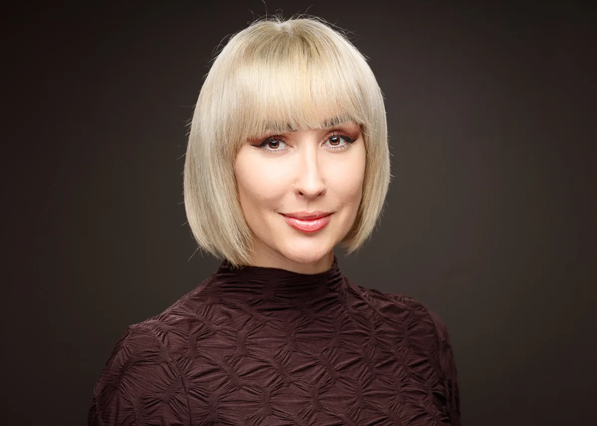 Woman with short blonde hair, wearing a dark top.