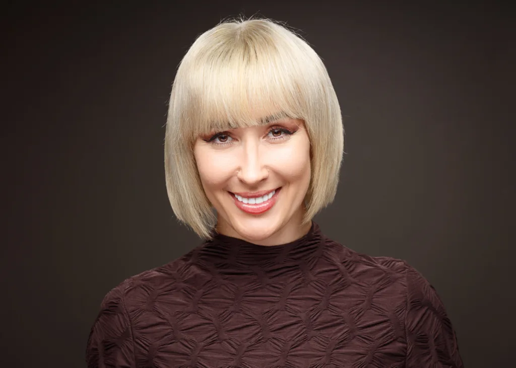 Smiling person with blonde bob haircut.