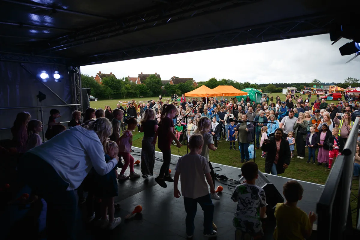 Children performing on outdoor stage at community event.
