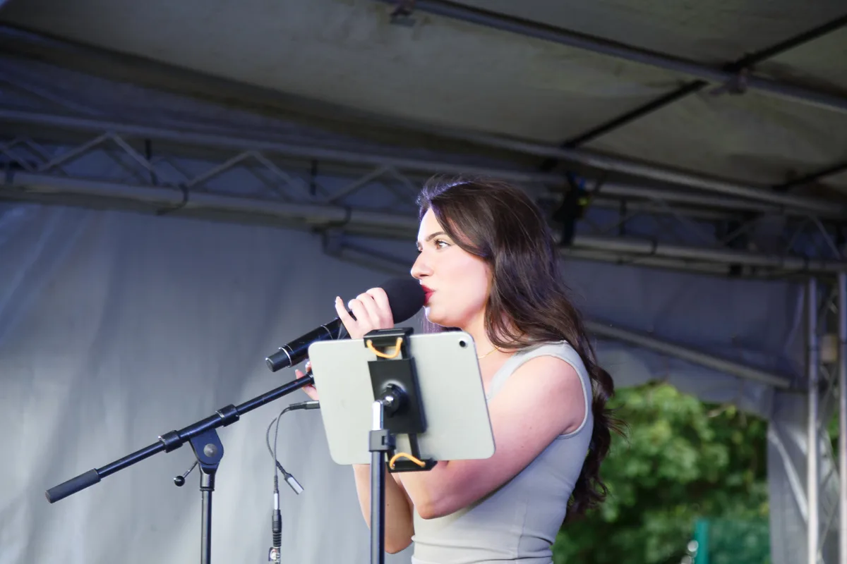Woman singing on stage with microphone.