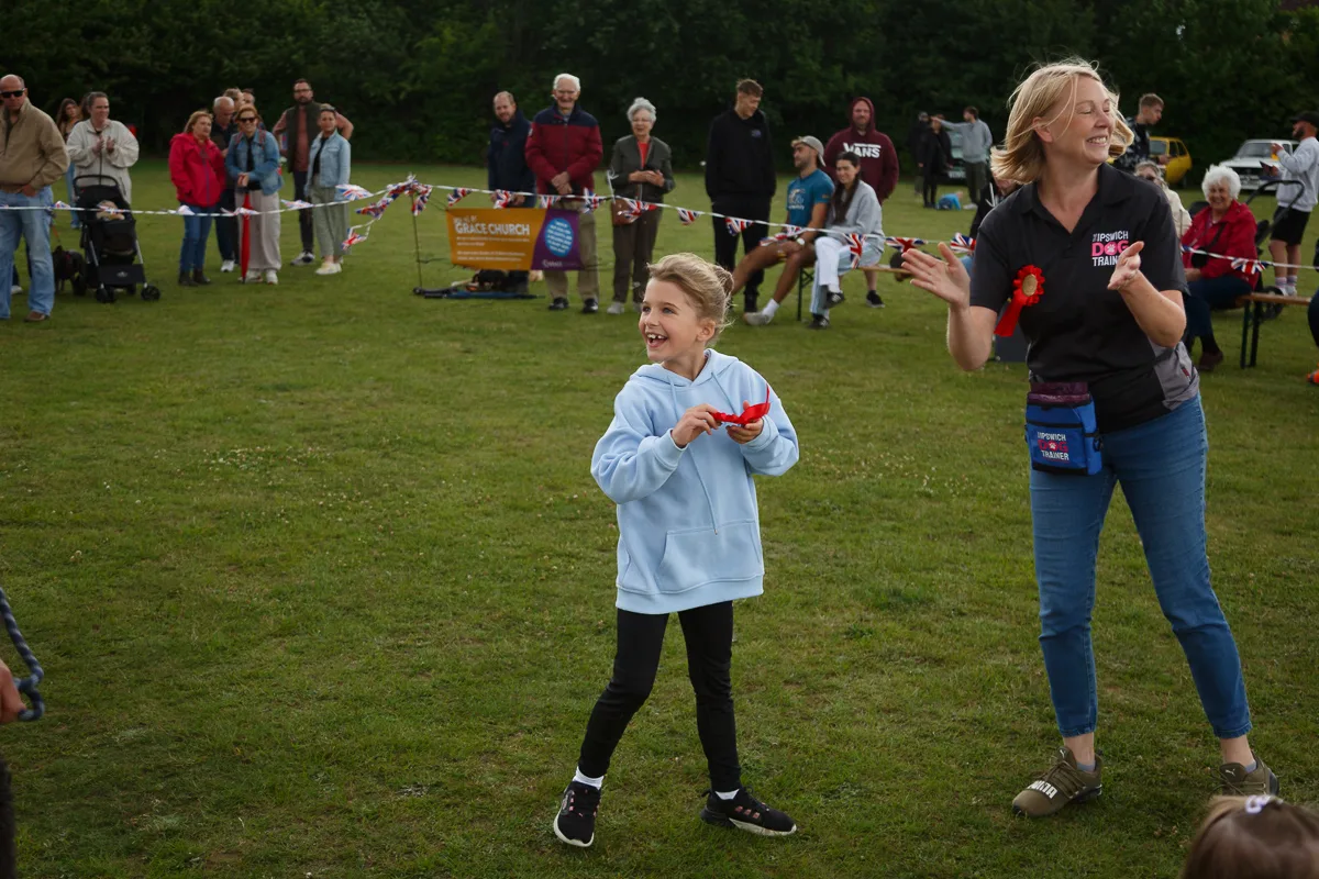 Child playing at outdoor event with crowd cheering.