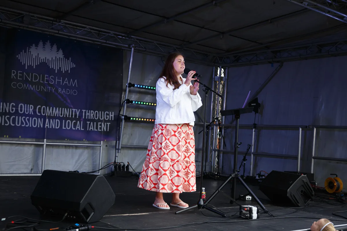 Woman singing on stage at community event.