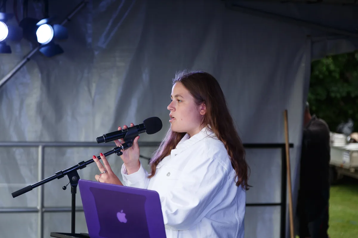 Woman speaking into microphone on stage.