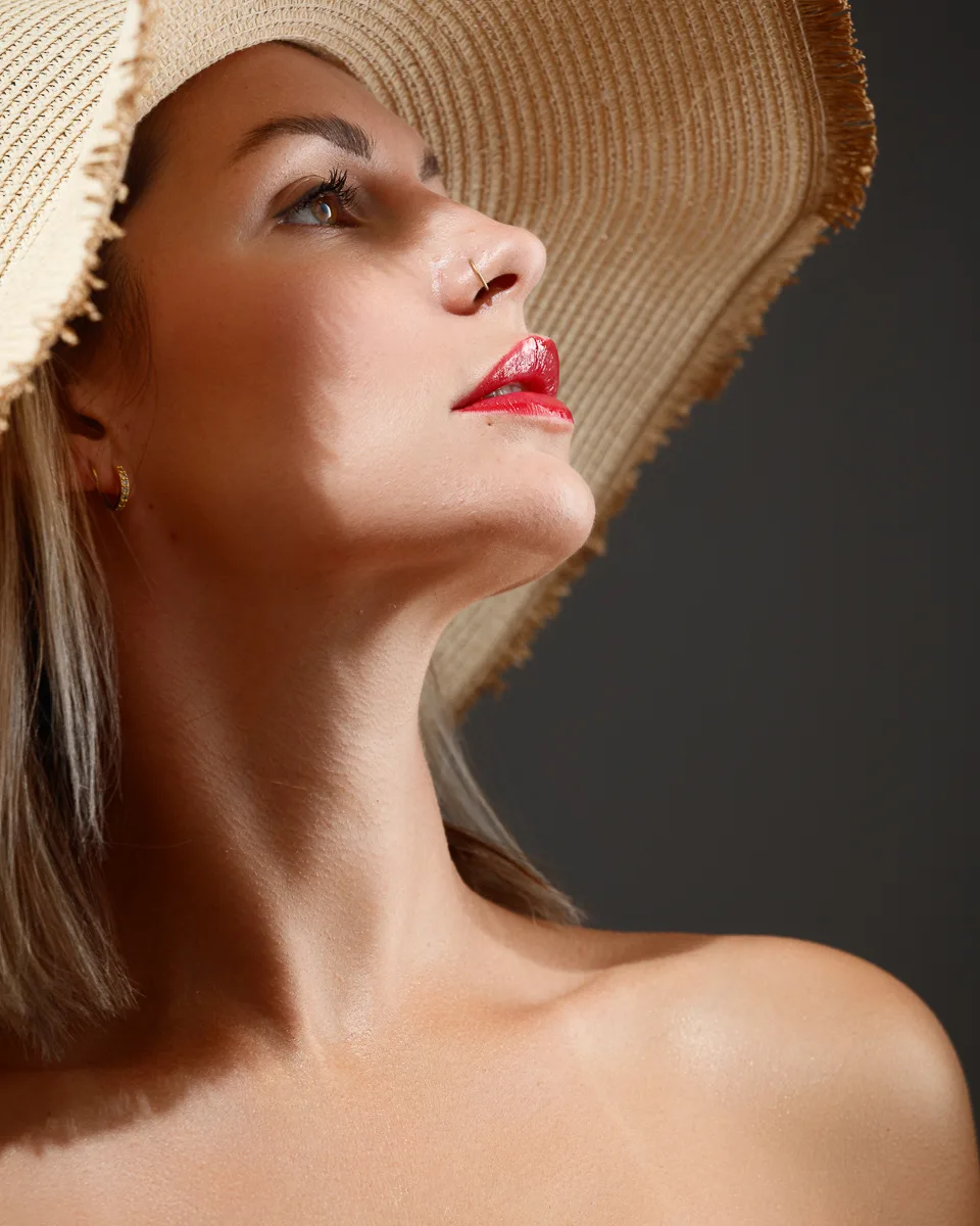 Woman wearing large straw hat and red lipstick.