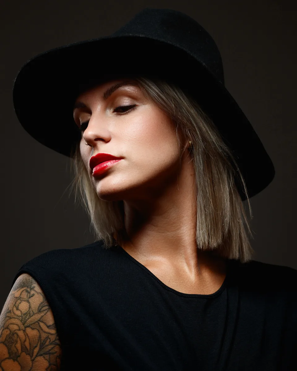 Woman with hat, red lipstick, and tattoo.