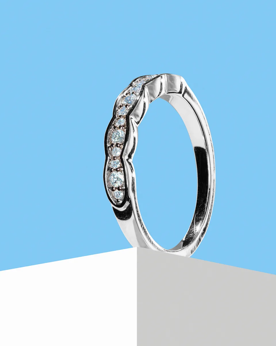 Silver ring with diamonds on a white surface.