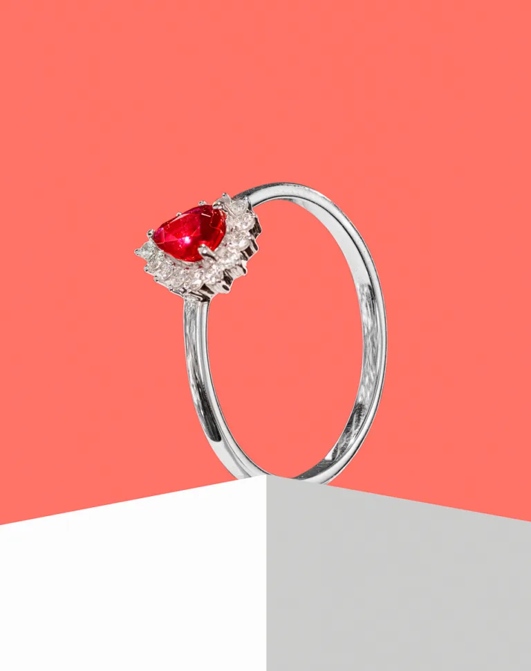 Silver ring with a red gemstone and diamonds.